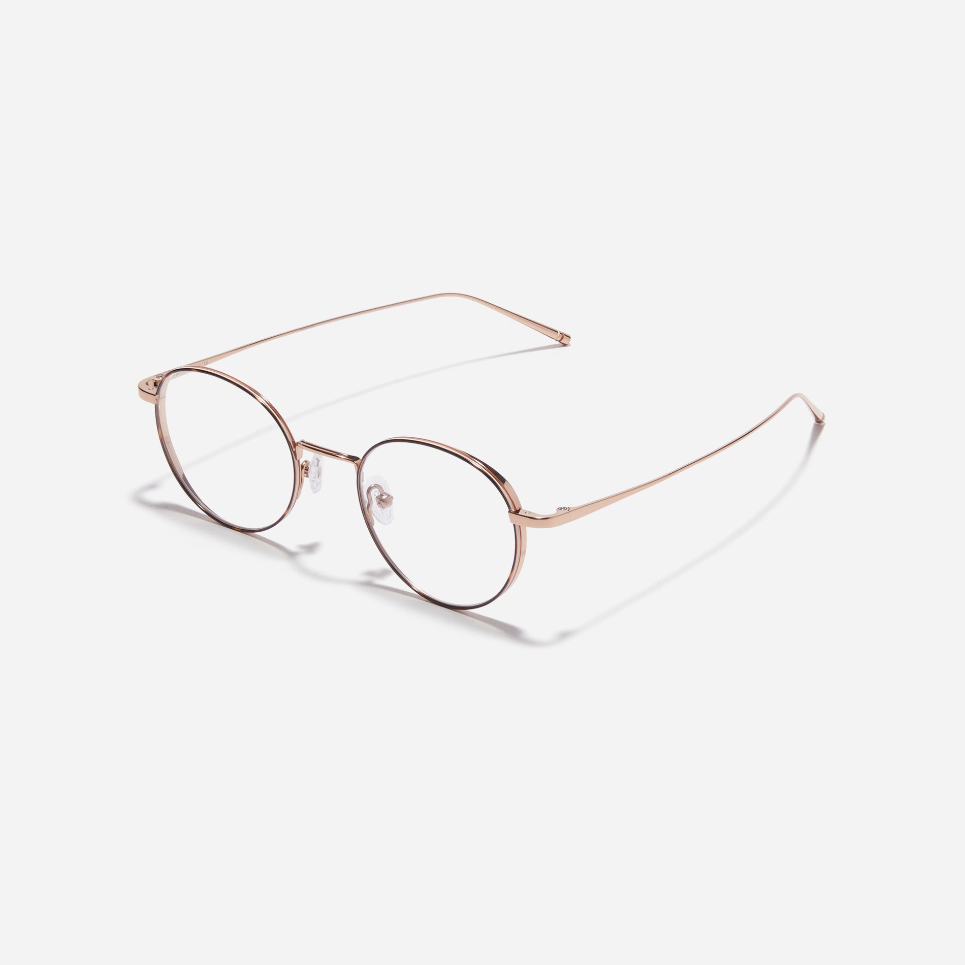 Round-shaped titanium eyeglasses inspired by the aesthetics of platform shoes. Their dual-rim structure effortlessly accommodates the use of thick lenses for higher prescriptions, while retro vibes shine through side color accents applied using epoxy techniques.